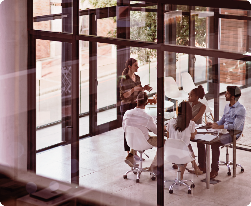 Group of professionals in a meeting inside a modern office with glass walls.